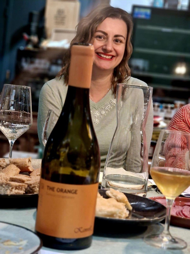 Een gast achter een fles orange wine aan de proeftafel