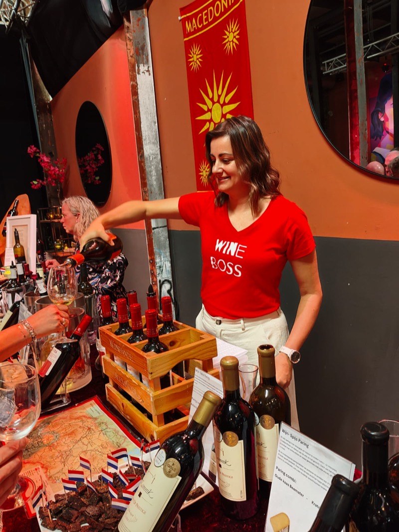 Biljana schenkt wijn in bij een Macedonische stand op een wijnevenement