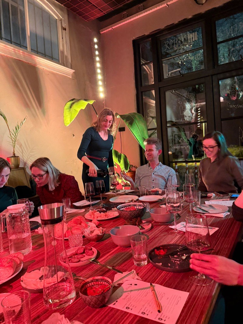 Gasten aan een lange tafel terwijl er wijn wordt ingeschonken